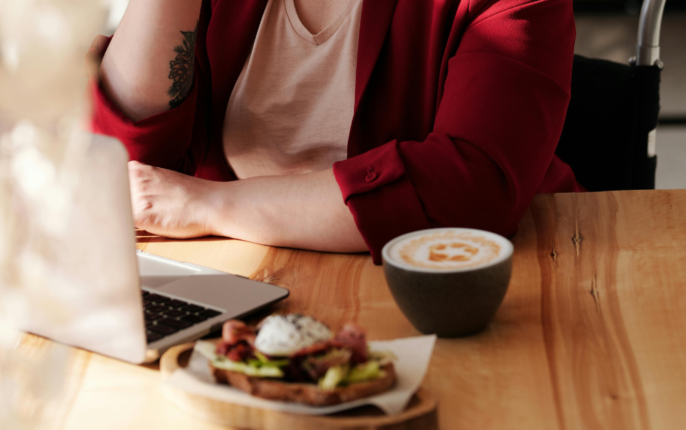 Frau arbeitet im Café mit Sandwich und Cappuccino